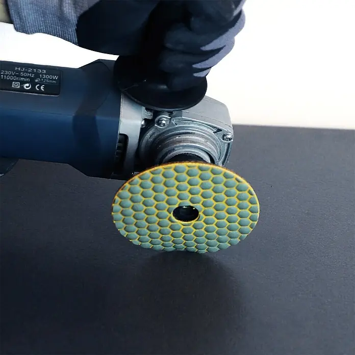 Bihui Diamant-Schleifteller DPP420 - Körnung: 200, Durchmesser: 100 mm - Winkelschleifer mit gelb-grünem hexagonalem Polierpad, von einer behandschuhten Hand gehalten.