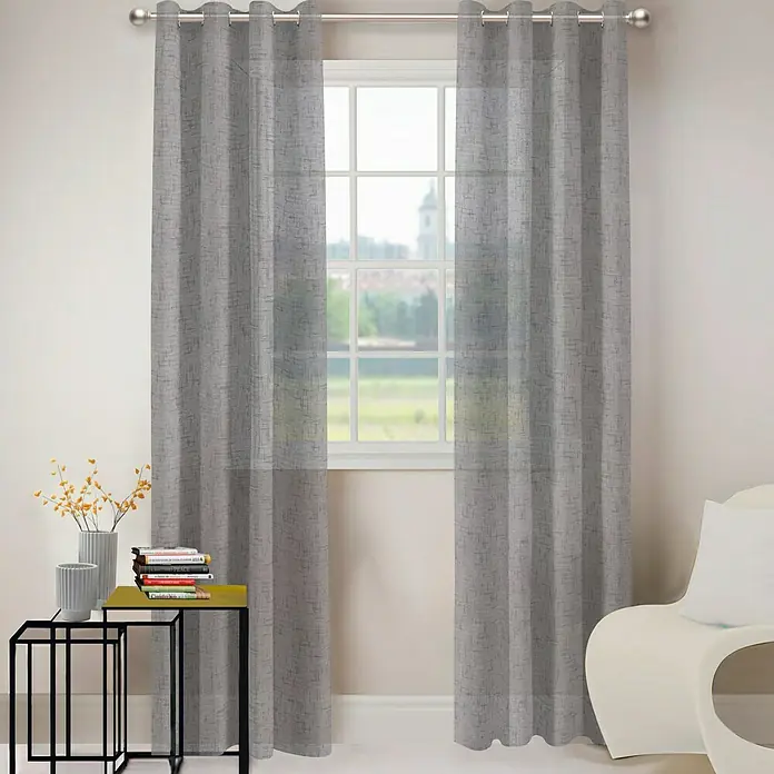 Visillo para ventana Luciole - 140 x 250 cm, 100% poliéster, Gris - Cortinas grises cuelgan frente a una ventana, ofreciendo privacidad y filtrado de luz con un aspecto elegante y moderno para cualquier habitación.