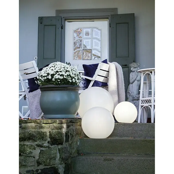 8 Seasons Design Shining LED-Dekoleuchte rund Globe - 6 W, Weiß, Durchmesser: 30 cm - Eine stilvolle Außendekoration mit leuchtenden Kugellampen auf einer Treppe vor einem Haus, kombiniert mit Pflanzen und rustikalem Dekor.