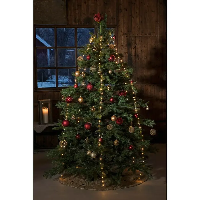 Konstsmide LED-Lichterkette Baummantel - Innen, Lichtfarbe: Bernstein, Anzahl Leuchtmittel: 240 Stk., Netzbetrieben - Festlich geschmückter Weihnachtsbaum im Innenraum, beleuchtet mit goldenen und roten Kugeln und warmen Lichtern.