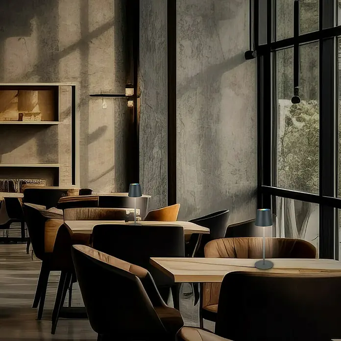 Brilo Akku-Tischleuchte Cilano - L x B x H: 15 x 42 x 36 cm, RGBW, 3 Stk., Schwarz - Zwei kabellose Tischleuchten mit Akku auf Tischen in einem Restaurant, die eine gemütliche Atmosphäre schaffen.