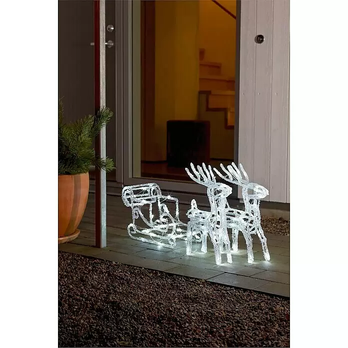 Konstsmide LED-Weihnachtsdekoleuchte Rentiere mit Schlitten - Transparent, Netzbetrieben, LED - Beleuchtetes weißes Rentier- und Schlitten-Weihnachtsdekorationsset auf einer Terrasse bei Nacht.