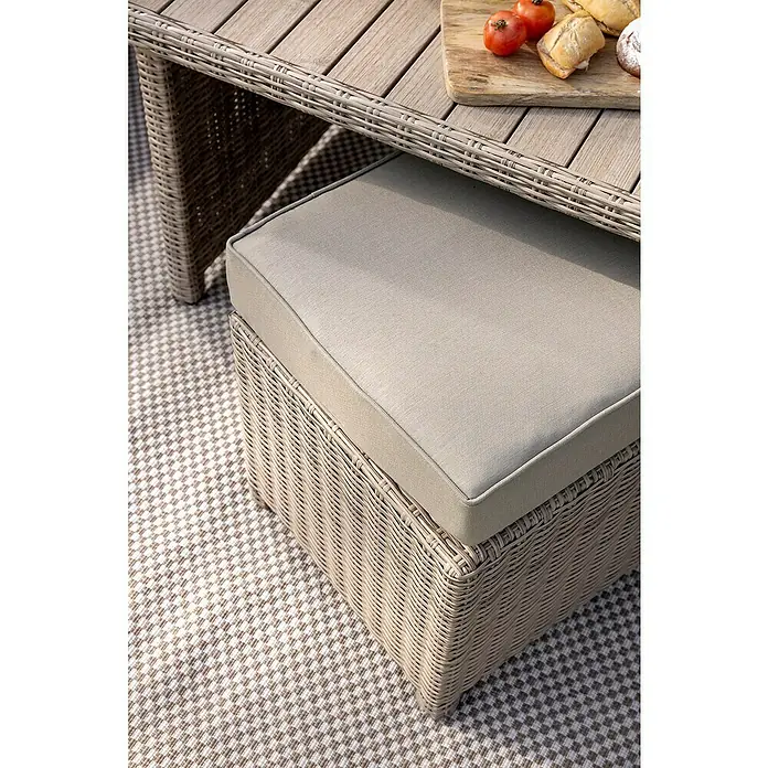 Sunfun Conjunto de muebles Portland III - 6 pzs., Ratán sintético/Aluminio, Crema - Primer plano de una otomana con cojín y una mesa con comida encima.