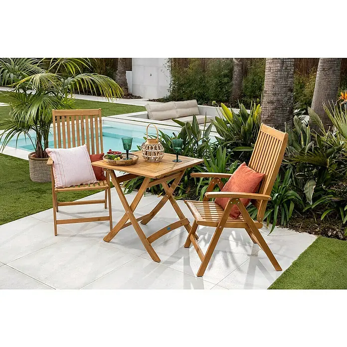 Mesa de jardín Zaira - L x An x Al: 70 x 70 x 74 cm, Teca, Natural, Abatible - Una mesa cuadrada de madera con dos sillas a juego, decorada con vasos y fruta, situada al aire libre en un patio.