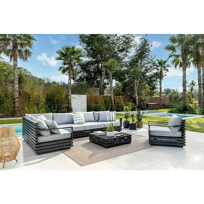 Sunfun Loungemöbel-Set Bea - 7 -tlg., Weiß/Hellgrau - Elegante Gartenmöbel-Gruppe mit grauen Polstern und dunklem Rahmen, umgeben von Palmen und üppigem Grün. Ideal für entspannte Stunden im Freien.