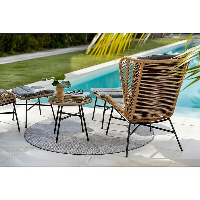 Alfombra exterior reversible Vichy - Gris, Diámetro: 160 cm, Polipropileno - Vista de una moderna silla de ratán con cojín gris, una mesa auxiliar con decoración y taburetes en la piscina.
