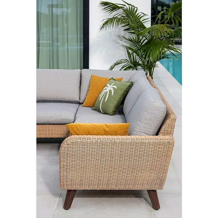 Sofá de conjunto Royal Riviera - Beige, An x Pr x Al: 234 x 89 x 75 cm, Aluminio/Ratán sintético - Primer plano de un sofá esquinero de mimbre marrón claro con cojines grises y cojines decorativos amarillos y verdes con estampado de palmeras.