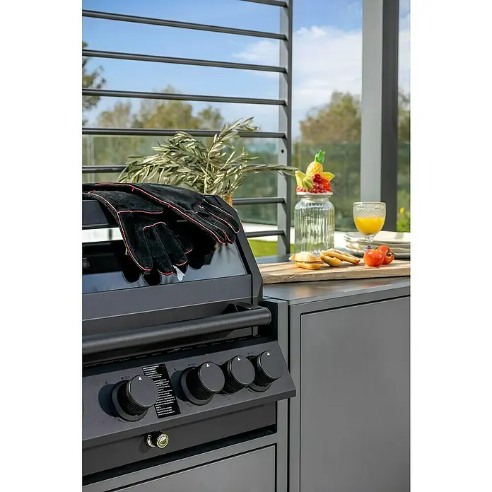 Sunfun Cocina exterior con estantería Kendra - Aluminio/Acero, Antracita - Primer plano de una parrilla negra con controles, guantes y comida, ideal para barbacoas relajadas al aire libre.