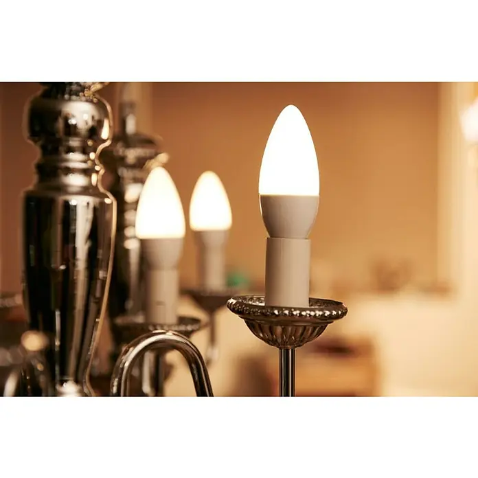 Philips Bombilla LED - Blanco diurno, 470 lm, 5,5 W - Primer plano de bombillas LED en forma de vela en una lámpara de araña brillante, emitiendo luz cálida.