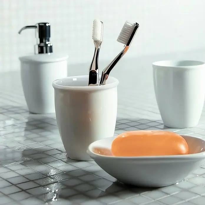 Spirella Escobillero de suelo Atlanta - Porcelana, Blanco - Primer plano de cepillos de dientes, jabón y dispensador en una estantería de baño.