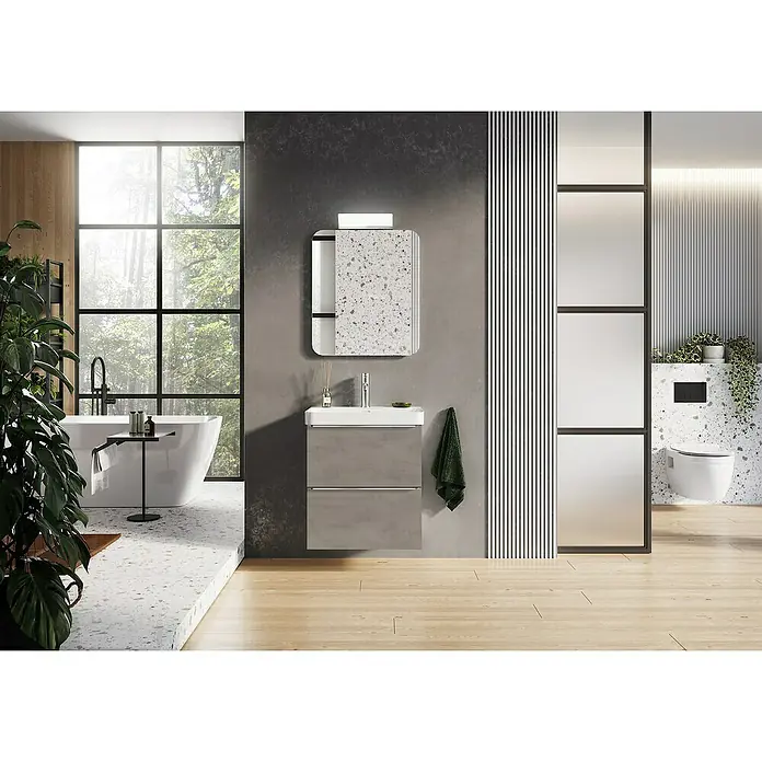 Riva Beauty 2.0 Waschtischunterschrank - B x T x H: 58,5 x 43,7 x 63,5 cm, Chromix Silver - Elegantes Badezimmer mit einem modernen Waschtisch in Grau, einem Spiegel mit Terrazzo-Muster und einer freistehenden Badewanne vor einem grossen Fenster.