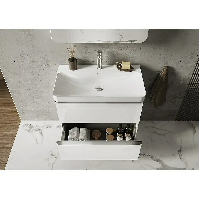 Riva Beauty 2.0 Waschtischunterschrank - B x T x H: 78,5 x 43,7 x 63,5 cm, Weiß Matt - Ein moderner, weißer Waschtisch mit offenem Schubfach, das Handtücher und Pflegeprodukte zeigt, vor einer stilvollen Badezimmerkulisse.