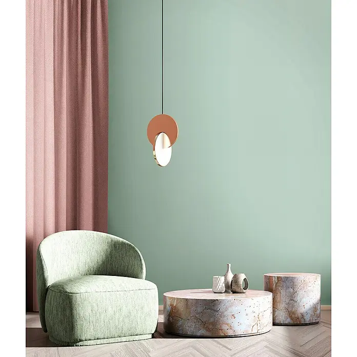Glööckler Pompöös Provence Vliestapete - Grün, Uni, 10,05 x 0,53 m - Ein modernes Wohnzimmer mit einem stilvollen Lampenpendel, einem mintgrünen Sessel und Marmortischen, die eine ruhige und elegante Atmosphäre schaffen.