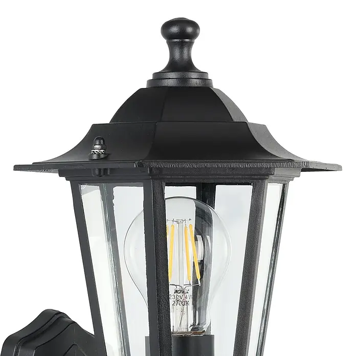 Eglo Laterna 4 Außenwandleuchte - 60 W, Schwarz, Klar, IP44, Bewegungsmelder - Detailaufnahme einer schwarzen Außenleuchte mit klaren Glasscheiben und einer Glühbirne im Retro-Stil. Elegantes Design für den Außenbereich.