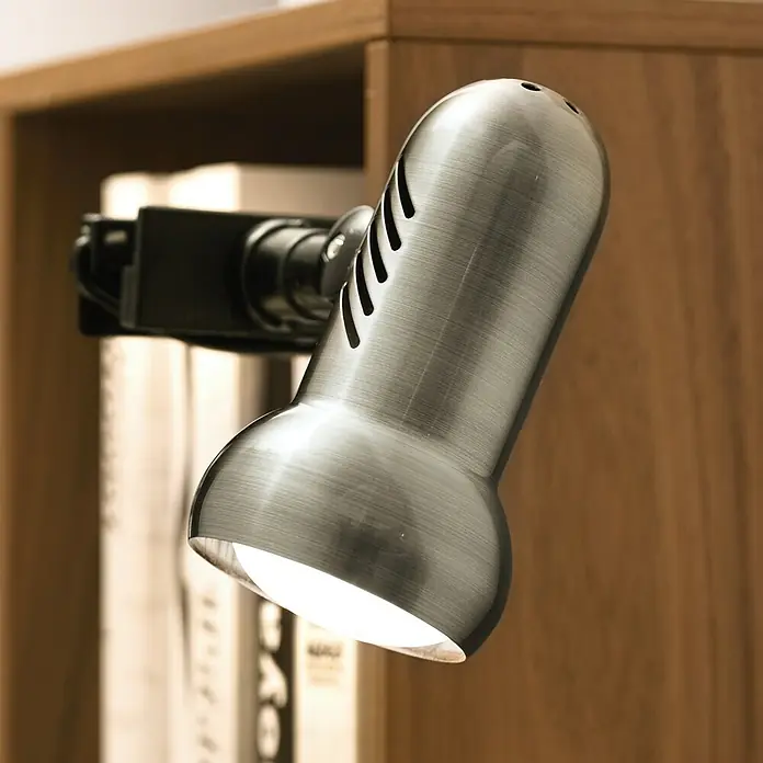 Eglo Klemmleuchte Manhatten - 60 W, Farbe Gehäuse: Nickel matt - Nahaufnahme einer modernen silbernen Leselampe mit LED-Licht, die an einem Regal befestigt ist und Bücher beleuchtet.