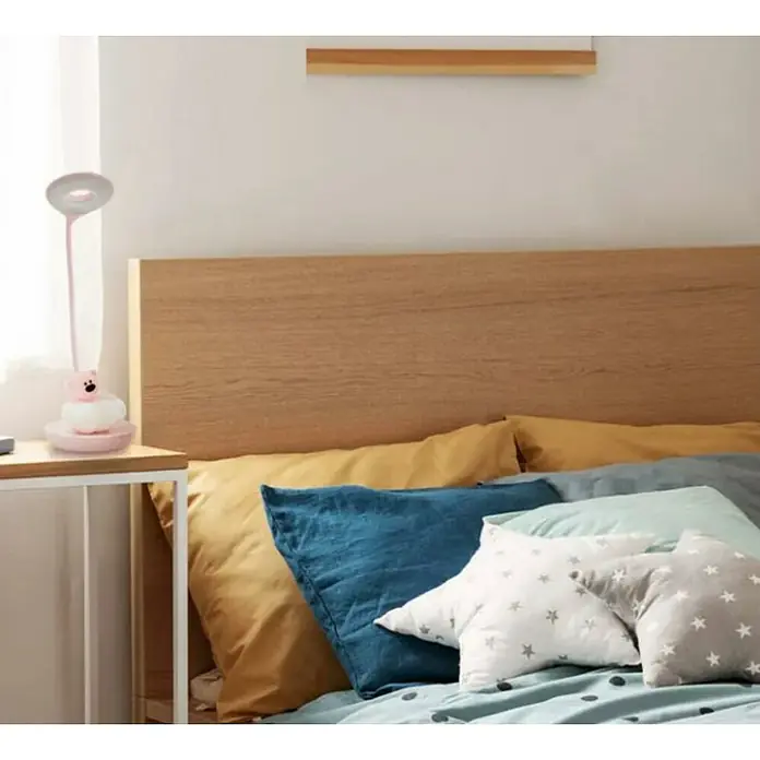 Idp Lampshades Lámpara de sobremesa LED Nestor - 3 W, L x An x Al: 13 x 13 x 22 cm, Rosa - Una lámpara de noche con diseño de oso está sobre una mesita de noche junto a una cama con muchas almohadas.