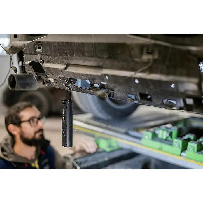 Ledlenser LED-Arbeitsleuchte W5R Work - 600 lm, Lichtfarbe: Kaltweiß, IP54 - Schwarze Arbeitsleuchte hängt zur Inspektion unter einem Fahrzeug.