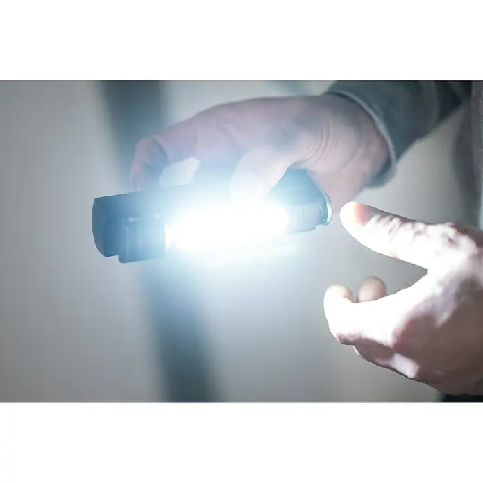 Ledlenser LED-Arbeitsleuchte W6R Work - 500 lm - 600 lm, Lichtfarbe: Kaltweiß, IP54 - Hand hält eine dunkle Taschenlampe mit starkem, leuchtendem Strahl.