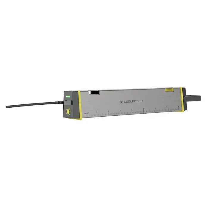Ledlenser LED Baustrahler AF2R WORK - 1.000 lm, 6.000 K - 7.000 K, 4,6 x 3,8 x 24,8 cm, IP54 - Graues LEDLENSER Gerät mit gelben Akzenten, Lineal und angeschlossenem USB-Kabel. Grüne Ladeanzeige leuchtet.