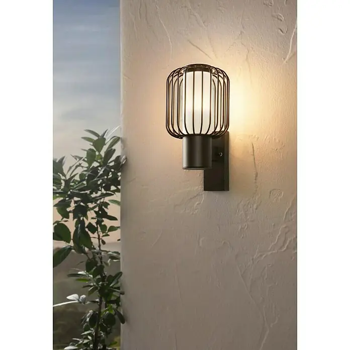 Eglo Ravello Aplique exterior - 60 W, 16,5 x 16,5 x 27,5 cm, Negro, IP44 - Primer plano de una elegante lámpara de pared para exteriores que presenta un diseño moderno con forma de jaula que emite un brillo cálido, creando un ambiente acogedor.
