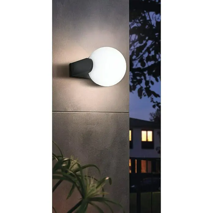 Eglo Aplique exterior Rubio - 15 W, Negro, IP44 - Una moderna lámpara de pared esférica para exteriores que proyecta una luz cálida sobre una pared texturizada, creando un ambiente acogedor.