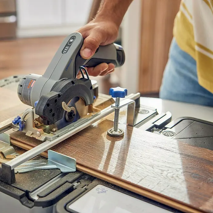Dremel Aserradero móvil Blueprint - 12 V, 1 batería, 2 Ah, Número de revoluciones de marcha en vacío: 5.000 r.p.m. - Un primer plano de una sierra circular Dremel cortando un trozo de madera, la herramienta está firmemente sujeta en la mano del usuario.