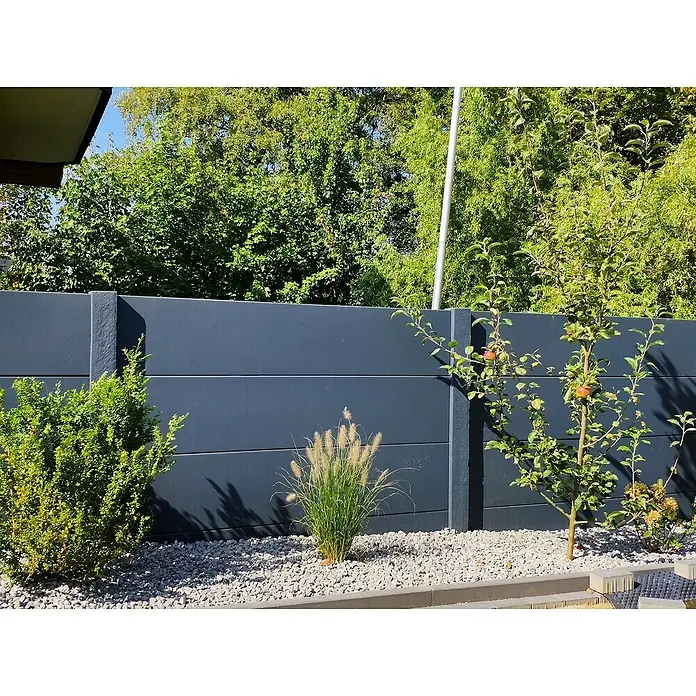Beckers Betonzaun Zaunelement Standard glatte Platte - 200 x 38,5 cm, Beton, Betongrau - Eine graue Betonzaunanlage mit horizontalen Linien, die eine moderne und schlichte Gartengestaltung unterstreicht. Die Bepflanzung lockert das Bild auf.