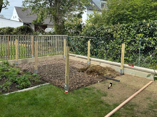 Holzpfähle wurden mithilfe von Bodenhülsen in die Erde gesteckt um als Pfosten für das DIY Foliengewächshaus zu dienen