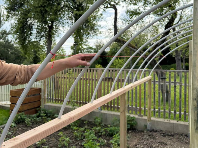 Kunststoffstangen werden am DIY Foliengewächshaus Holzrahmen befestigt und dienen später als Gerüst für die Bedachung