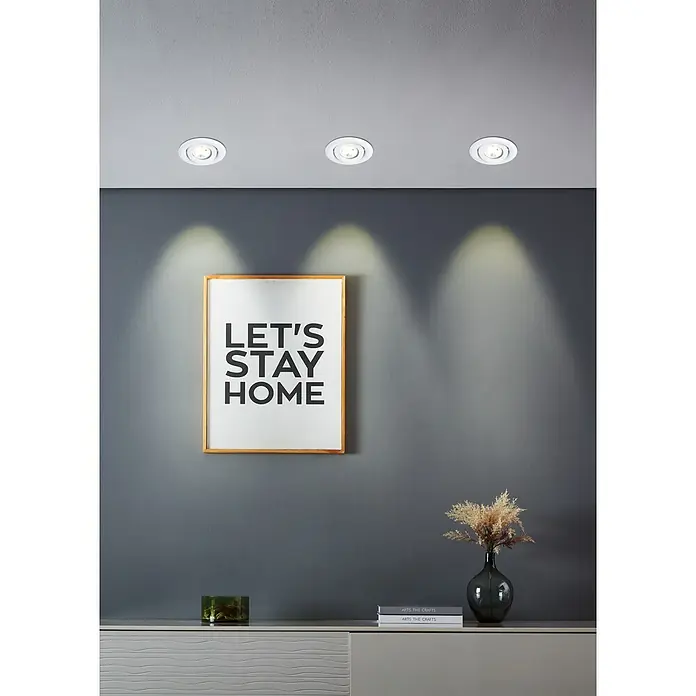 Eglo LED-Einbauleuchten-Set rund SALICETO MINI-PUCK 2 - 4,2 W, Ø x H: 7,7 x 2,3 cm, Weiß, Warmweiß - Deckenleuchten erhellen ein modernes Interieur mit einem gerahmten "Let's Stay Home"-Poster und dekorativen Akzenten auf einer Kommode.