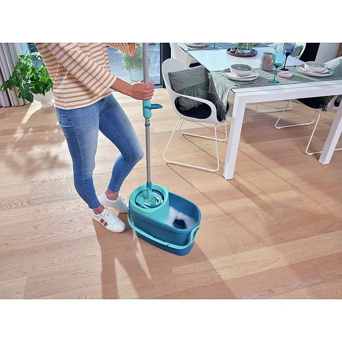 Leifheit Bodenwisch-Set Clean Twist M Ergo - 4 -tlg., 6 l - Bild einer Person, die mit einem türkisfarbenen Wischmopp-Set einen Holzboden reinigt, wobei der Fokus auf dem Mopp-Eimer liegt.