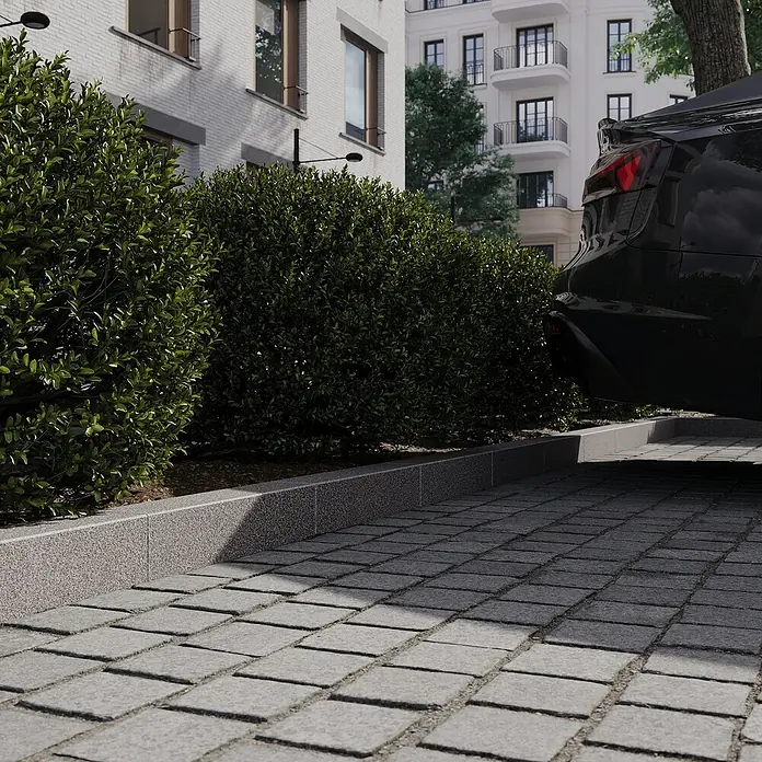 Palisade G 654 - 50 x 10 x 12 cm, Anthrazit - Nahaufnahme von grauem Pflaster und grünen Büschen, die einen gepflegten Außenbereich mit einem Hauch von Natur und moderner Ästhetik schaffen.