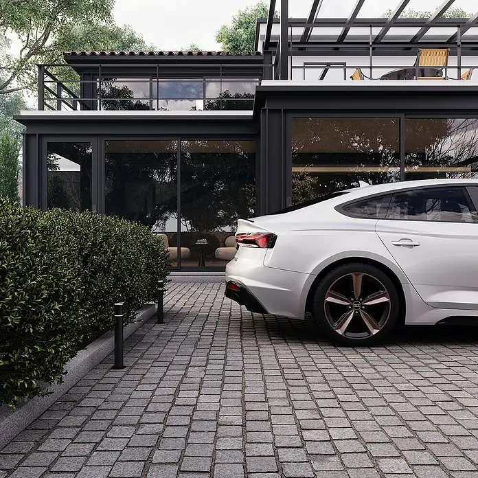 Granitpflaster G 654 - Anthrazit, 10 x 10 x 4 cm - Ein weißer Audi parkt vor einem modernen Haus mit großen Fensterfronten und einem gepflasterten Hof. Elegantes Design trifft auf Komfort.