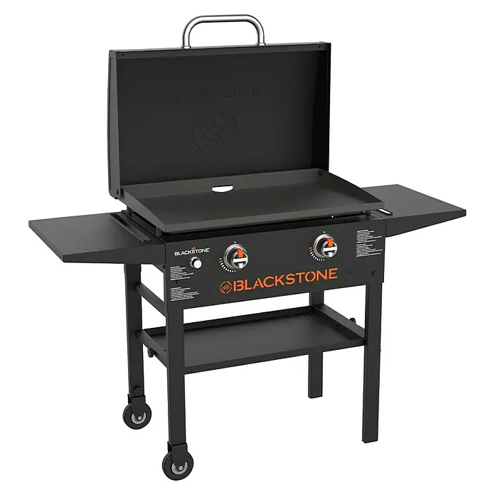 Blackstone Plancha-Grill 28" mit Haube - Grillfläche (B x T): 73 x 46,3 cm, 10 kW, Schwarz - Das Bild zeigt einen schwarzen Blackstone Grill mit offener Haube und Ablageflächen, ideal für Outdoor-Kocherlebnisse.