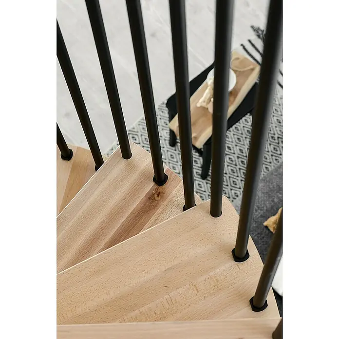 Minka Spindeltreppe Spiral Effect - Durchmesser: 140 cm, Schwarz, Farbe Stufen: Buche Natur, Geschosshöhe: 305,5 cm - Detailaufnahme einer Holztreppe mit schwarzen Metallgeländern, die ein modernes und stilvolles Designelement hervorheben.