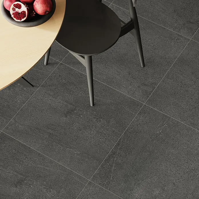 Terrassenfliese Patio - 60 x 60 x 2 cm, Anthrazit, Matt - Nahaufnahme des modernen, dunklen Fliesenbodens mit einem Stuhl und einem Tisch mit Obstschale.