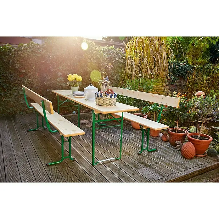 Sunfun Bierzeltgarnitur - 3 -tlg., Nadelholz/Stahl, Klappbar, Naturbraun/Grün, Tisch (L x B x H): 220 x 50 x 77 cm, Bank (B x T x H): 220 x 25 x 49 cm, Mit Rückenlehne - Ein Biertischgarnitur mit einem Holztisch und zwei Bänken mit grünen Metallbeinen auf einer Terrasse, dekoriert mit Blumen und Pflanzen.
