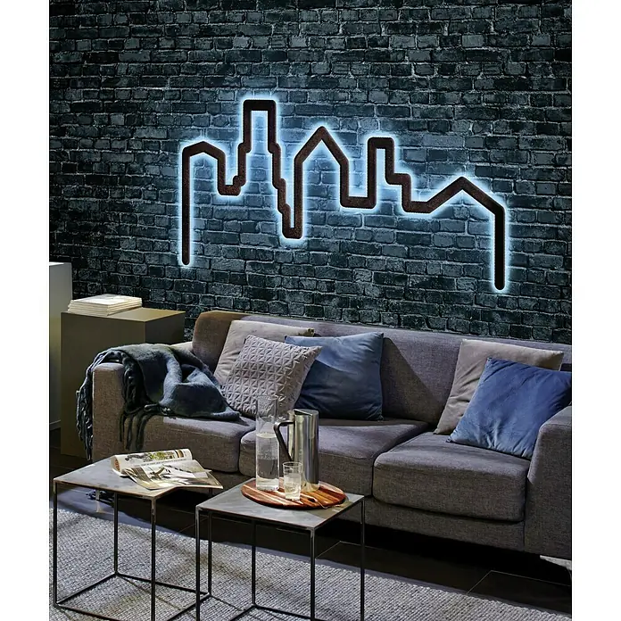 Paulmann LED-Band FlexLED 3D Basisset RGB - Länge: 1,5 m, Lichtfarbe: RGB, 11 W - Wanddeko im Wohnzimmer: Eine moderne Skyline-Silhouette mit blauer Neonbeleuchtung hängt über einem grauen Sofa und Beistelltischen.