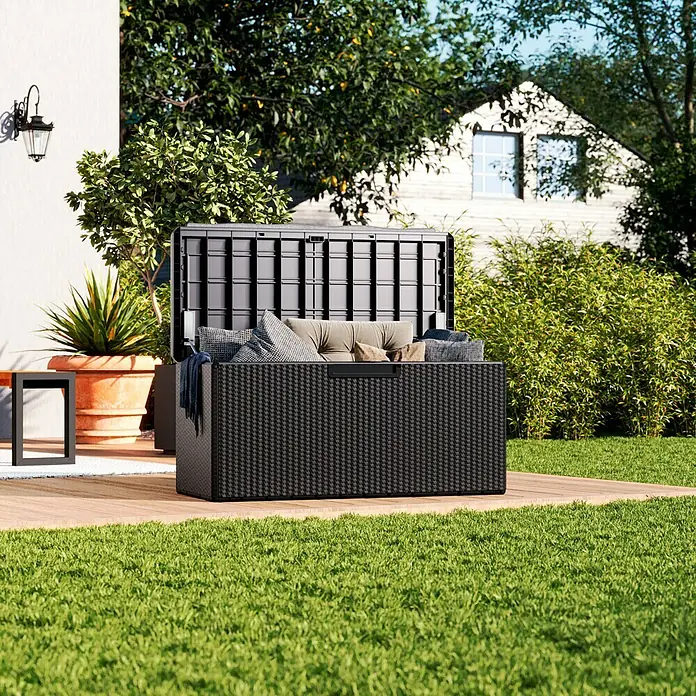 Toomax Gartenbox Portonovo - 124 x 55 x 59 cm, Kunststoff, Anthrazit, Behältervolumen: 350 l - Eine geöffnete schwarze Outdoor-Aufbewahrungsbox auf einer Holzterrasse, gefüllt mit Kissen und Decken.
