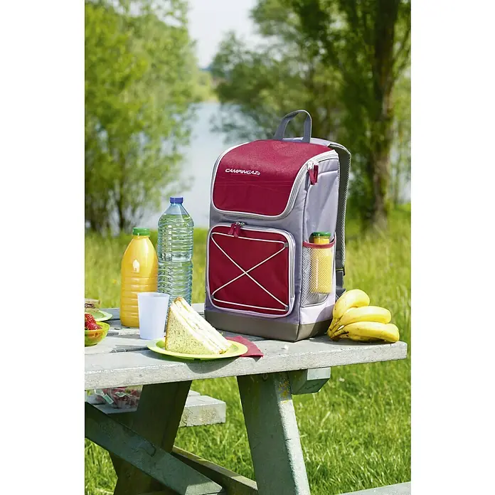 Campingaz Nevera portátil Urban picnic Bacpac 30l - Gris - Mochila nevera Campingaz, ideal para picnics al aire libre, sobre una mesa de picnic con comida y bebidas.
