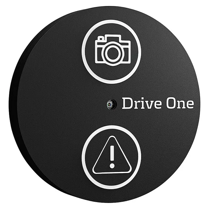 Needit Drive One - Mit Batterien - Schwarzes rundes Drive One Gerät mit texturierter Oberfläche, weißen Kamera- und Warnsymbolen.
