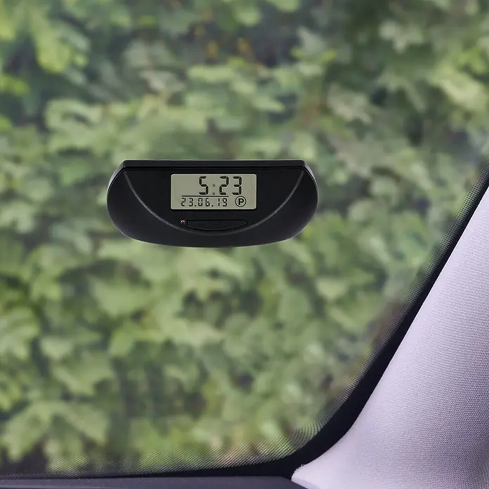 Needit Elektrische Parkscheibe Park Mini - Schwarz, Batteriebetrieben - Schwarze digitale Parkscheibe zeigt 5:23 und 23.06.19, im Auto montiert.