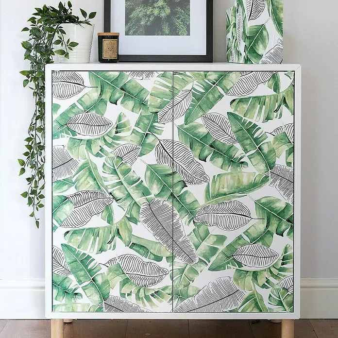 D-c-fix Rollo adhesivo vinílico Botánico Uva - 200 x 45 cm, Verde, Autoadhesivo - Armario decorativo con estampado de hojas verdes. El armario tiene marcos blancos y patas de madera y viene con plantas verdes y marcos de fotos.