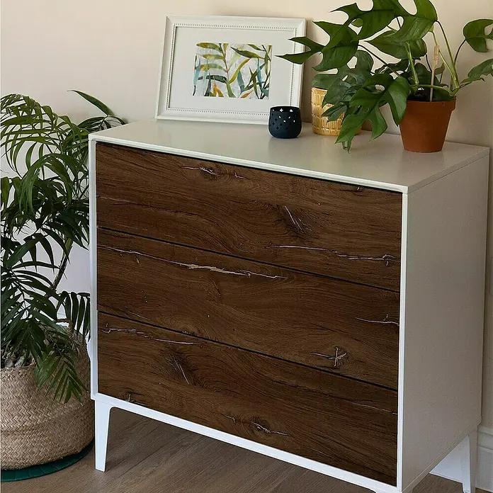D-c-fix Rollo adhesivo vinílico Roble Asta - 200 x 45 cm, Roble, Autoadhesivo - Una cómoda moderna con tres cajones con aspecto de madera y marco blanco, decorada con plantas y un cuadro.
