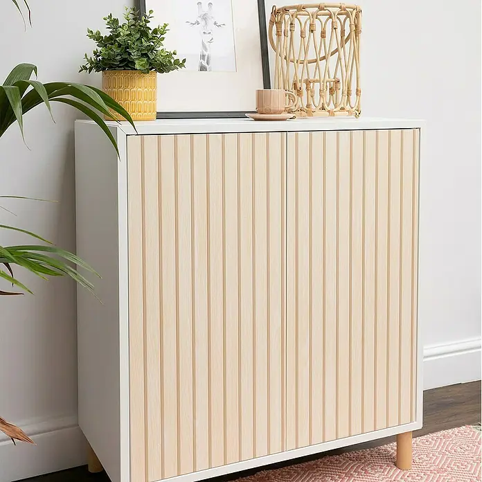 D-c-fix Rollo adhesivo vinílico Listones de madera - 200 x 45 cm, Marrón, Autoadhesivo - Armario blanco con puertas de listones de madera clara y elementos decorativos como una planta y una cesta encima.