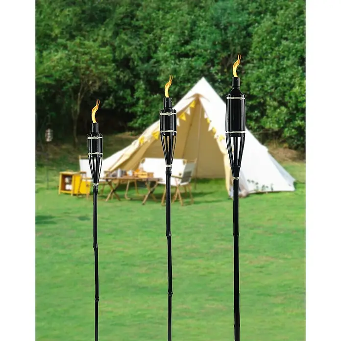 Bambusfackel - Höhe: 90 cm - Drei dekorative Bambus-Gartenfackeln mit Flammen vor einem Zelt im Grünen, ideal für stimmungsvolle Gartenbeleuchtung.