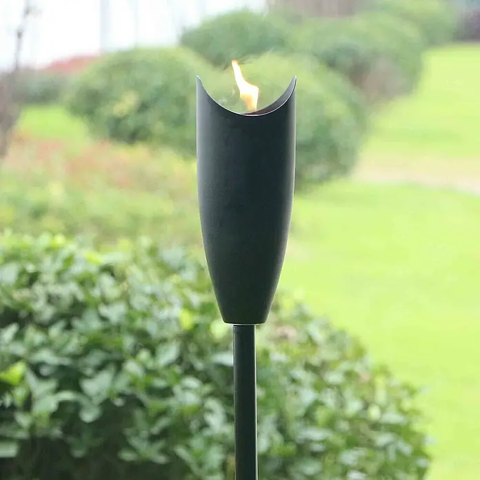 Gartenfackel - Ø x H: 10 x 150 cm, Edelstahl - Nahaufnahme einer schwarzen Gartenfackel mit Flamme. Die Fackel steht im Grünen und sorgt für eine stimmungsvolle Atmosphäre.