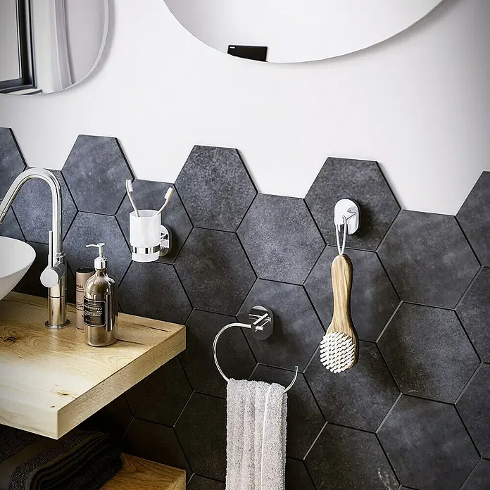 Aquasanit Link Toallero de anilla - Cromo, Resplandeciente - Primer plano de un baño elegante con accesorios, un toallero de anilla y un cepillo facial en una pared de azulejos hexagonales grises.