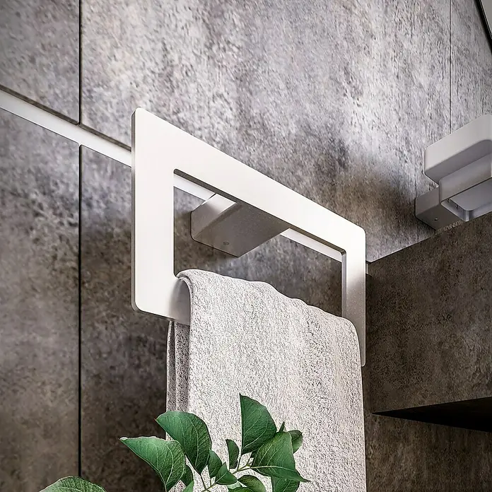 Toallero de anilla Leaf - Plateado, Resplandeciente - Un moderno toallero blanco con una toalla gris, combinando estilo y funcionalidad en el baño.\n