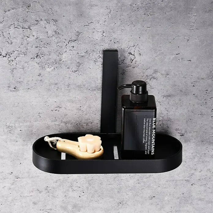 Aquasanit Evolution Cesta de baño -  - Un estante de pared ovalado negro con jabón, un cepillo y una botella marrón con dispensador negro.